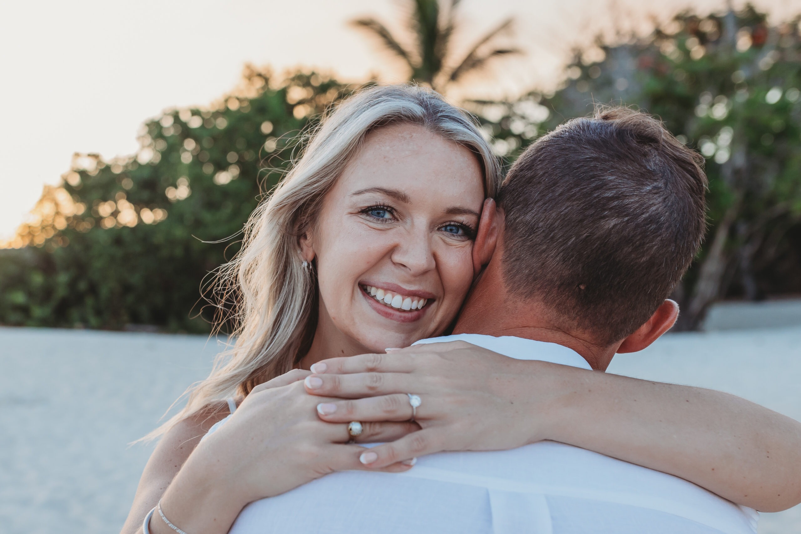 Newly engaged couple celebrating with a chilled bottle of premium champagne on the sand, captured by a professional proposal photographer.