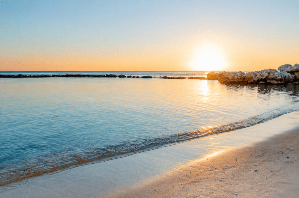 Pristine Caribbean beach in La Romana, Dominican Republic, with clear turquoise water and a sandy shore, perfect for a romantic sunset maternity photoshoot by a La Romana photographer.