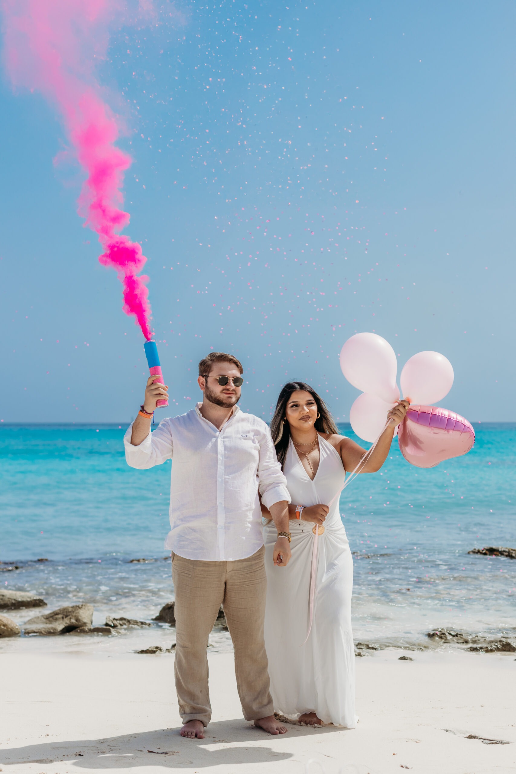 La Romana maternity photographer capturing a beach gender reveal with pink smoke bomb in Bayahibe.