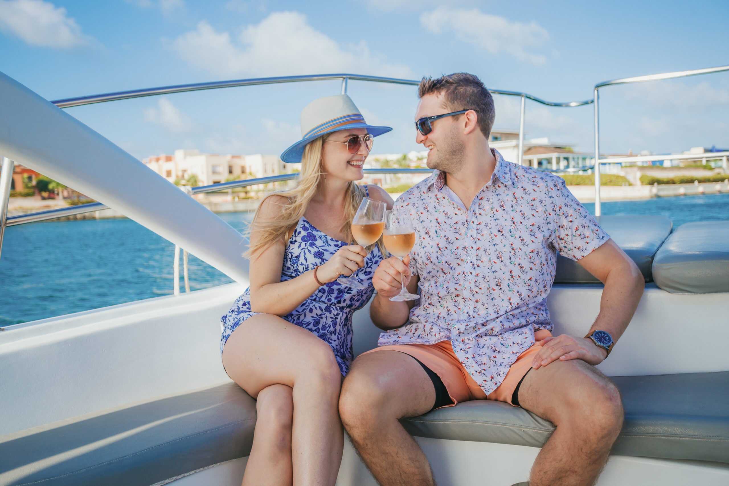 Happy engaged couple clinking wine glasses while relaxing on a luxury yacht deck in Cap Cana, captured by a La Romana photographer.